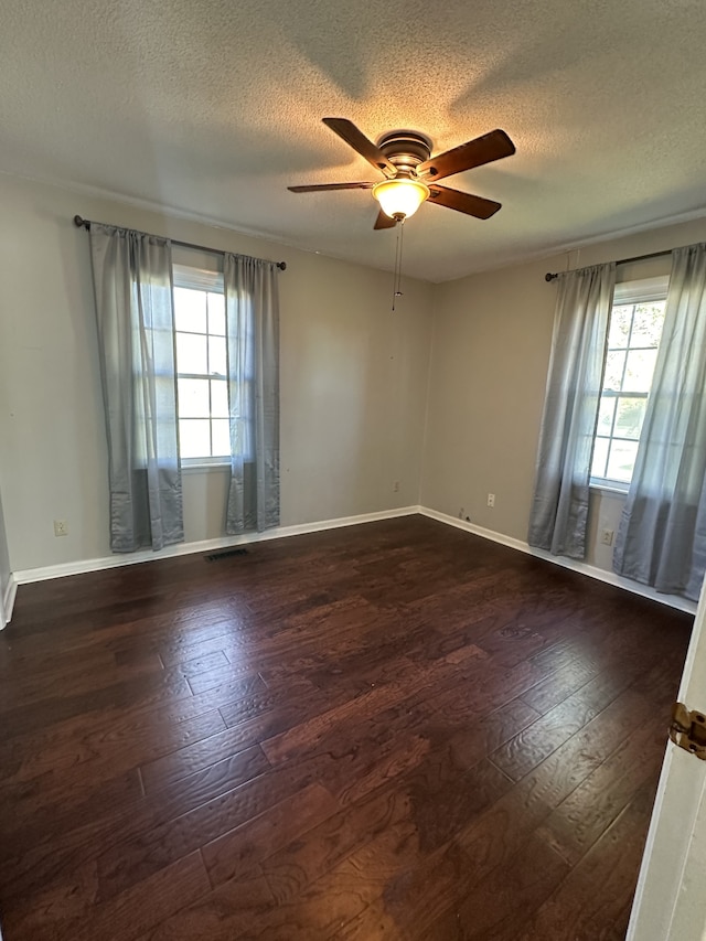 unfurnished room featuring a textured ceiling, ceiling fan, a healthy amount of sunlight, and dark hardwood / wood-style floors