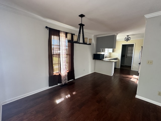 unfurnished living room featuring sink, dark wood-type flooring, crown molding, and a chandelier