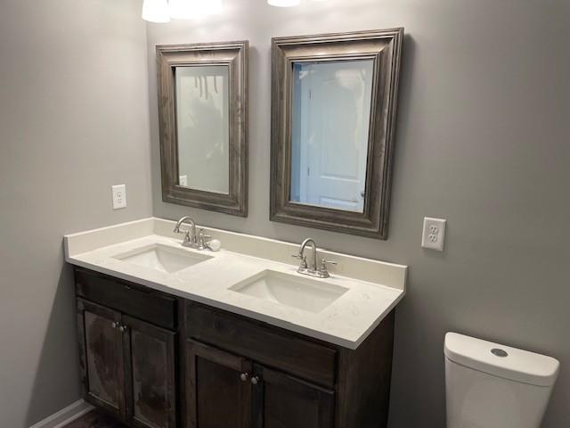 bathroom with double vanity, toilet, and a sink