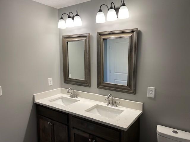 bathroom featuring toilet, double vanity, and a sink