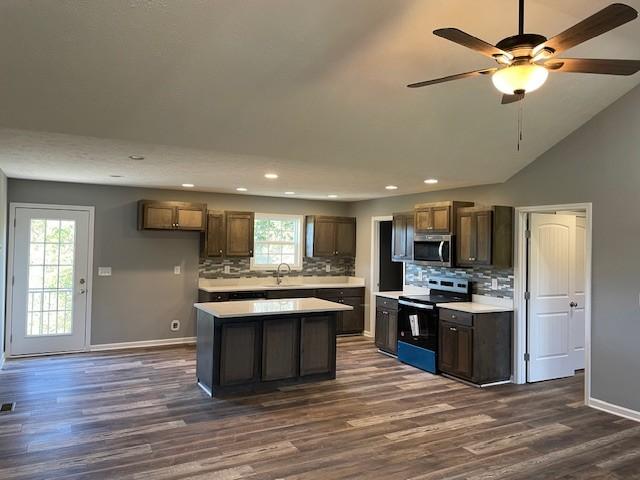 kitchen featuring stainless steel microwave, decorative backsplash, electric range, and light countertops