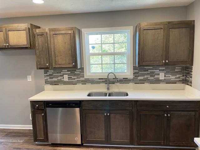 kitchen featuring decorative backsplash, dishwasher, dark wood-type flooring, and a sink