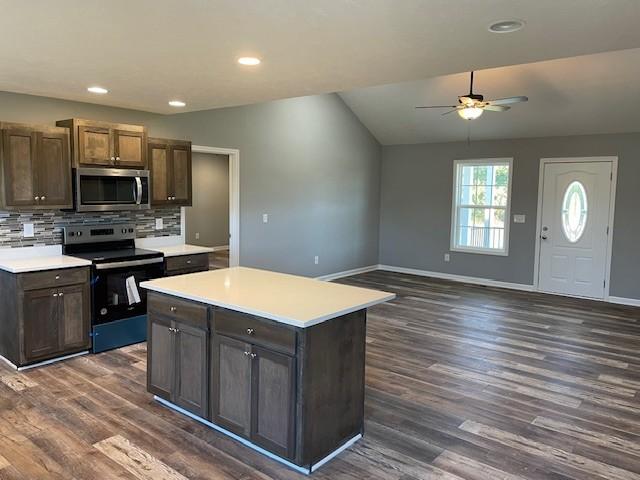 kitchen featuring tasteful backsplash, ceiling fan, stainless steel appliances, light countertops, and dark wood-type flooring