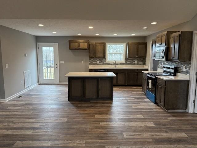 kitchen featuring range with electric stovetop, tasteful backsplash, stainless steel microwave, and dark wood-type flooring