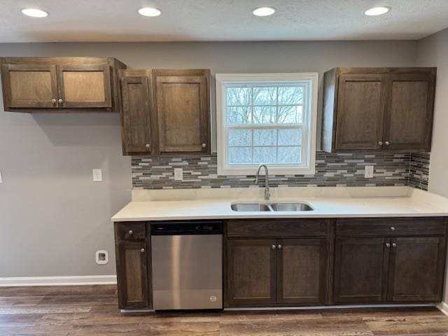 kitchen with tasteful backsplash, stainless steel dishwasher, a sink, baseboards, and dark wood-type flooring