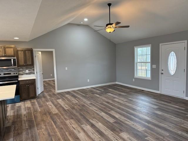 interior space with lofted ceiling, stainless steel appliances, light countertops, baseboards, and a ceiling fan