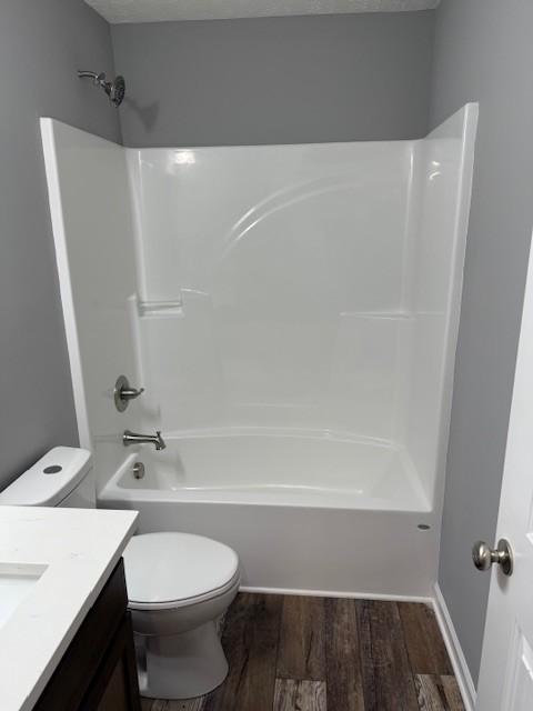 full bathroom with wood finished floors, toilet, vanity, and shower / bath combination