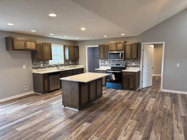 kitchen with dark wood-style floors, light countertops, tasteful backsplash, baseboards, and appliances with stainless steel finishes