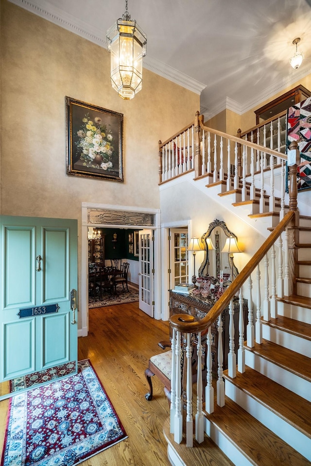 entrance foyer with ornamental molding, a notable chandelier, and hardwood / wood-style flooring