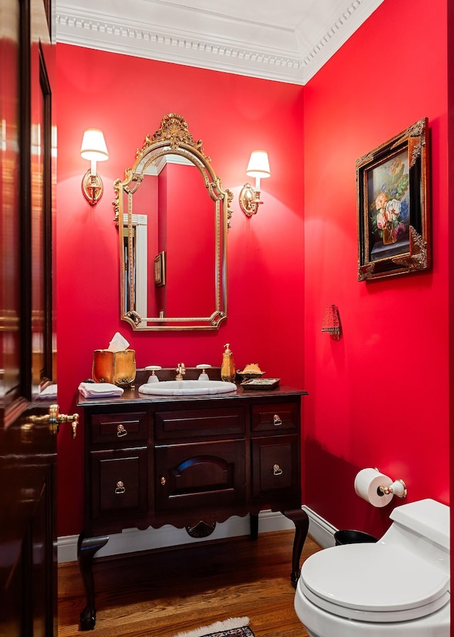 bathroom with toilet, hardwood / wood-style floors, vanity, and ornamental molding