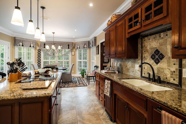 kitchen with sink, ornamental molding, hanging light fixtures, and an inviting chandelier