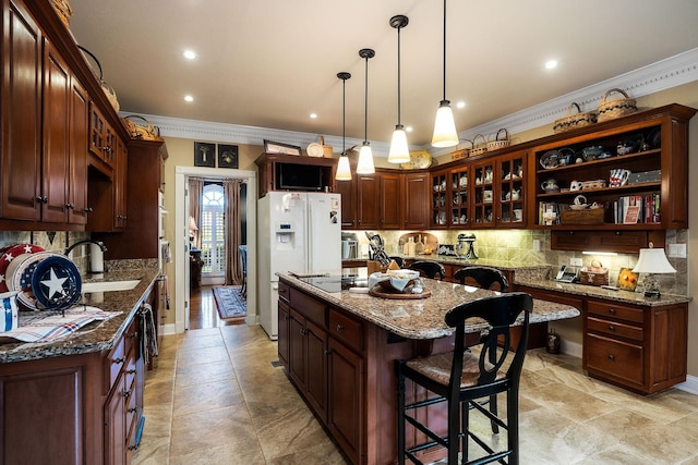 kitchen featuring a center island, sink, dark stone countertops, decorative light fixtures, and a breakfast bar area