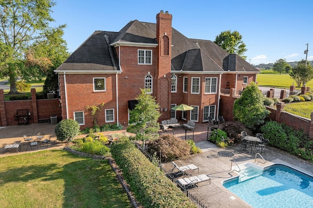 rear view of property with a fenced in pool, a patio area, a yard, and central AC