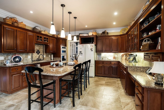 kitchen with decorative backsplash, double wall oven, dark brown cabinetry, white refrigerator with ice dispenser, and a center island