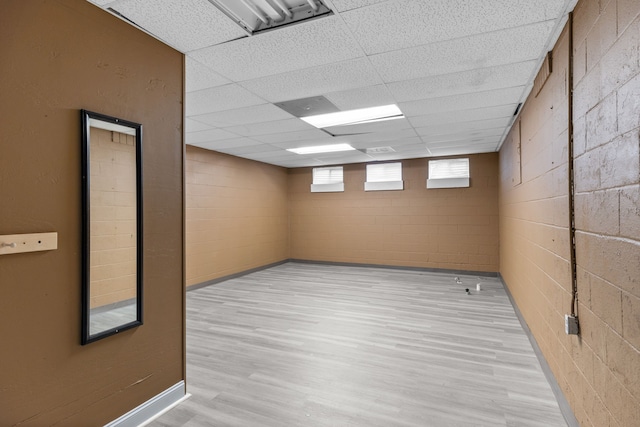 basement featuring light wood-type flooring and a paneled ceiling