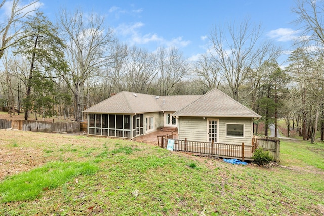 rear view of property featuring a sunroom, a lawn, and a wooden deck