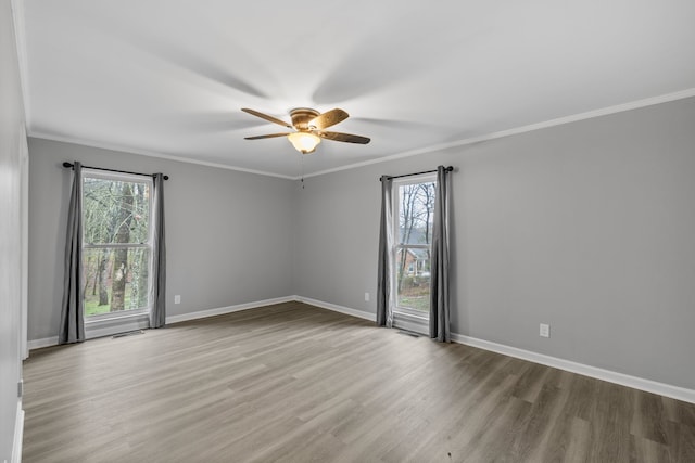 spare room with a wealth of natural light, ceiling fan, ornamental molding, and wood-type flooring