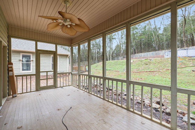 unfurnished sunroom with wood ceiling, plenty of natural light, and ceiling fan