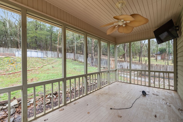 unfurnished sunroom featuring a healthy amount of sunlight, ceiling fan, and wooden ceiling