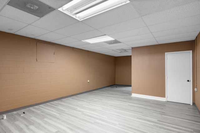 basement featuring a paneled ceiling and light hardwood / wood-style floors