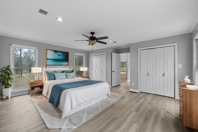 bedroom featuring two closets, ceiling fan, and light wood-type flooring