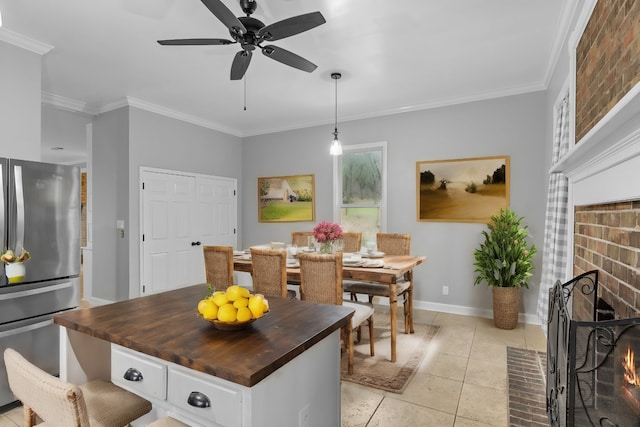 kitchen featuring a fireplace, stainless steel refrigerator, butcher block countertops, ceiling fan, and ornamental molding