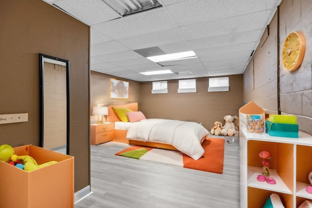 bedroom with wood-type flooring and a drop ceiling