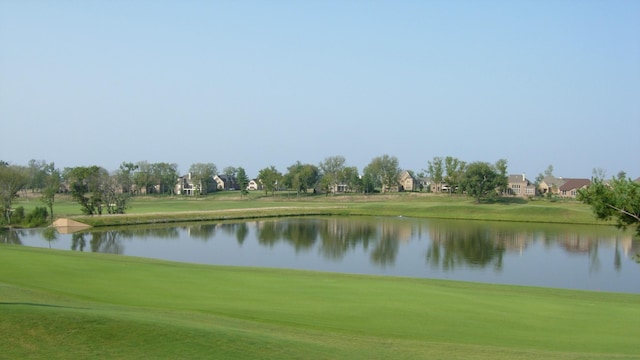 view of property's community with view of golf course, a water view, and a lawn