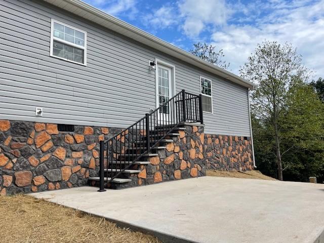 entrance to property with a patio, crawl space, and stone siding