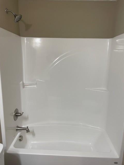 bathroom featuring washtub / shower combination and toilet