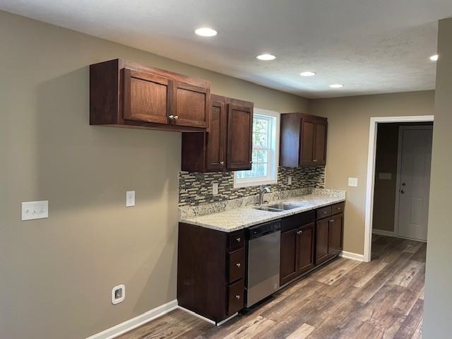 kitchen with stainless steel dishwasher, a sink, light countertops, wood finished floors, and backsplash