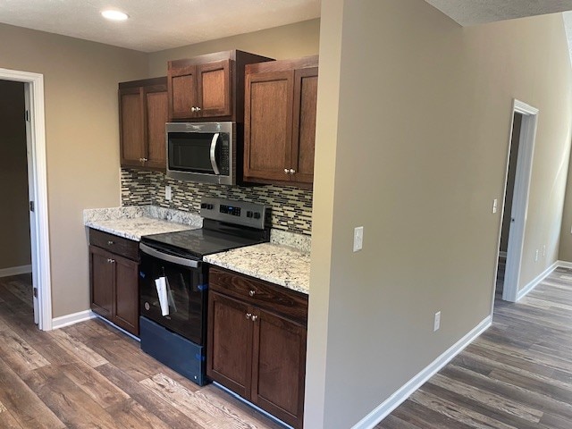 kitchen with light stone counters, dark wood-type flooring, electric stove, and decorative backsplash