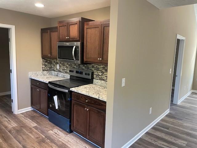 kitchen with tasteful backsplash, wood finished floors, electric range, and stainless steel microwave