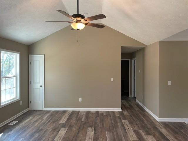 unfurnished room featuring dark wood-style floors, baseboards, ceiling fan, and vaulted ceiling