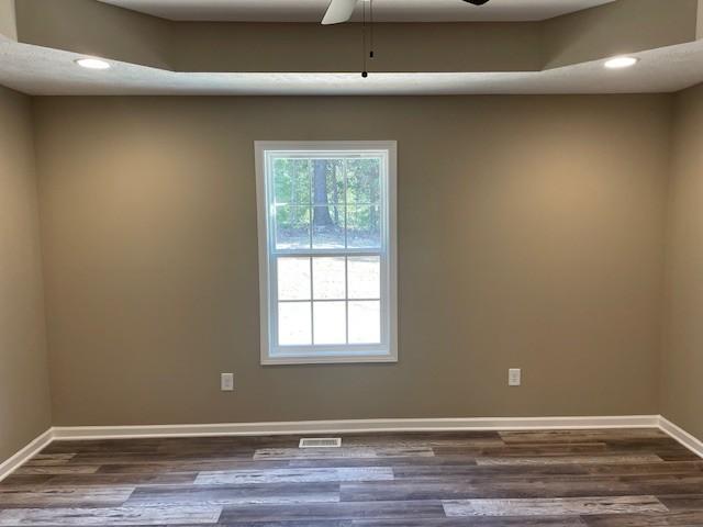 spare room with recessed lighting, visible vents, dark wood-style flooring, and baseboards