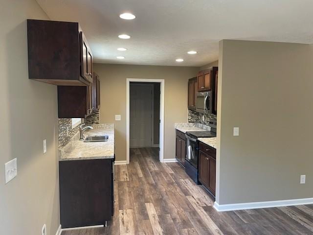 kitchen featuring stainless steel microwave, dark brown cabinetry, black electric range, and a sink