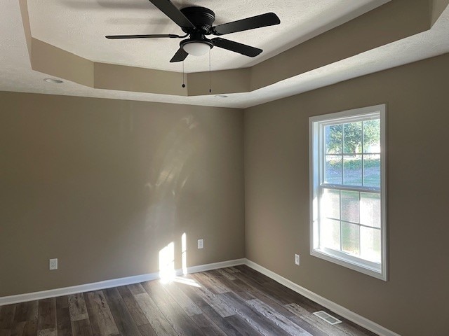 spare room featuring ceiling fan, a raised ceiling, dark hardwood / wood-style floors, and a textured ceiling