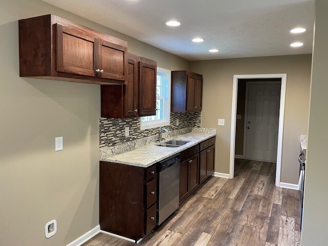 kitchen featuring stainless steel dishwasher, dark hardwood / wood-style floors, tasteful backsplash, dark brown cabinets, and sink