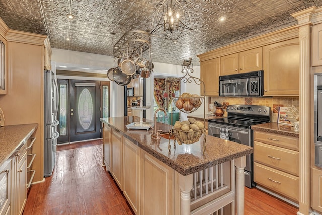 kitchen featuring backsplash, wood-type flooring, stainless steel appliances, and a center island with sink