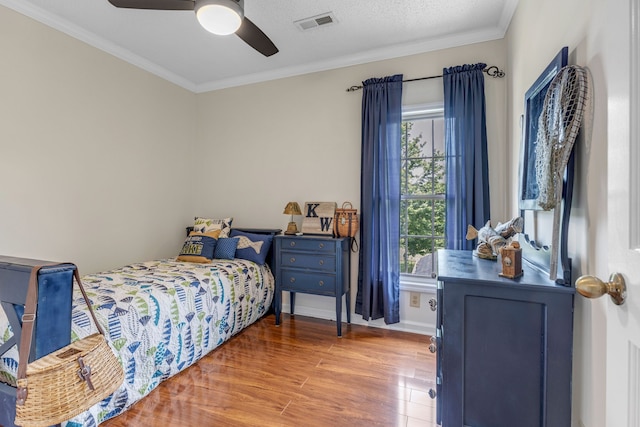 bedroom with crown molding, a textured ceiling, ceiling fan, and hardwood / wood-style floors