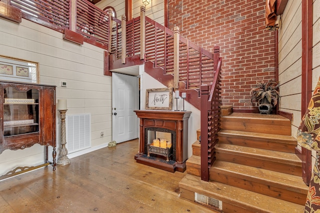 stairway featuring brick wall, hardwood / wood-style flooring, and a towering ceiling