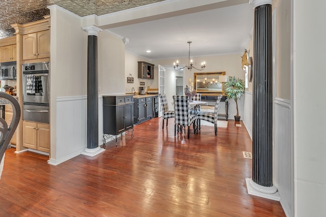 dining room featuring dark hardwood / wood-style flooring, ornate columns, and ornamental molding