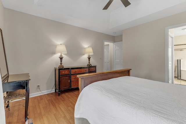 bedroom featuring light wood-type flooring, ceiling fan, and connected bathroom