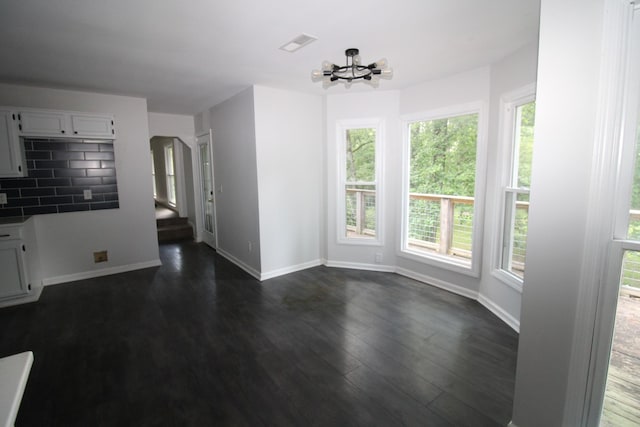 unfurnished dining area featuring a chandelier, a wealth of natural light, and dark wood-type flooring