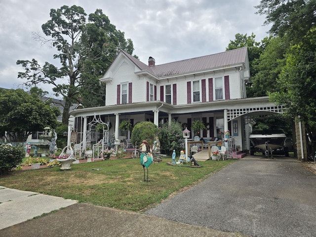 view of front facade with covered porch, a carport, and a front yard