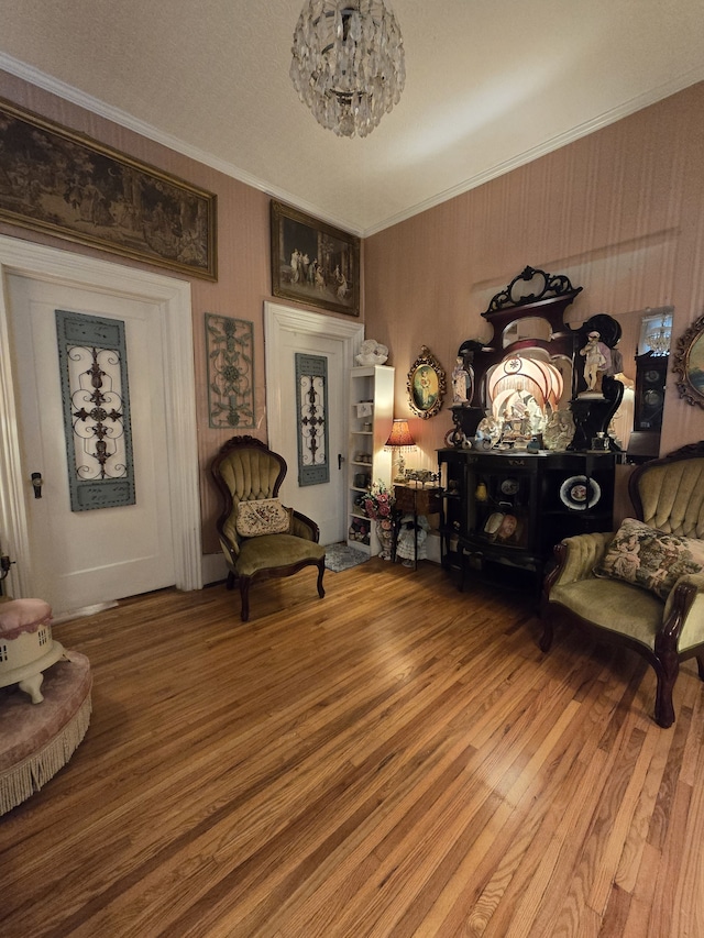 sitting room with ornamental molding, a textured ceiling, hardwood / wood-style floors, and a chandelier