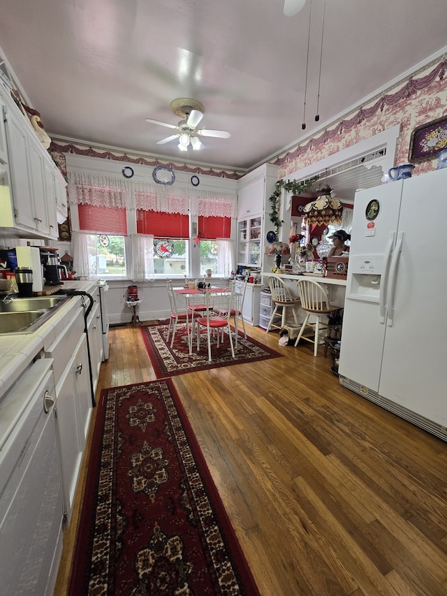 kitchen with white cabinets, hardwood / wood-style flooring, white fridge with ice dispenser, and ceiling fan