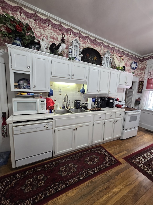 kitchen with white appliances, hardwood / wood-style floors, sink, decorative backsplash, and tile counters