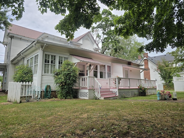 rear view of house with a wooden deck and a lawn