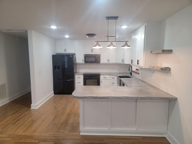 kitchen with kitchen peninsula, tasteful backsplash, black appliances, decorative light fixtures, and white cabinetry